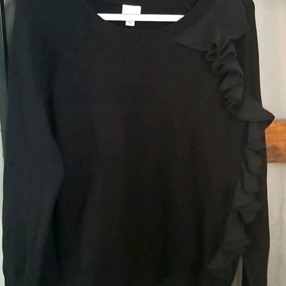 Black sweater has ruffles down the left side